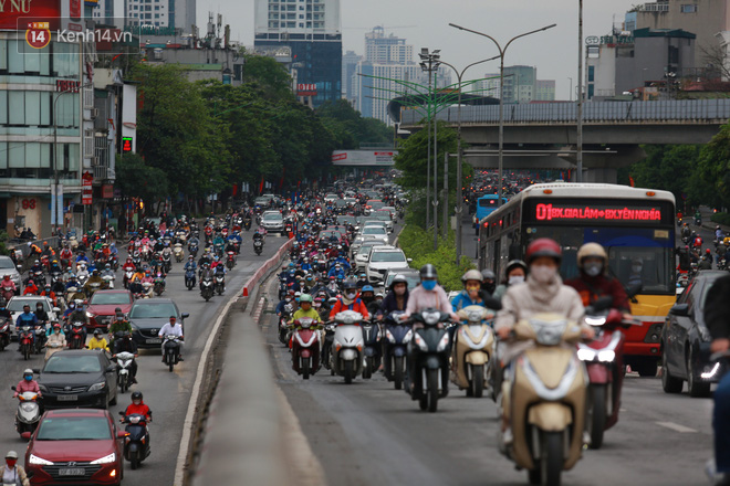 Ảnh: Đường phố Hà Nội và Sài Gòn đông đúc trong ngày đầu tiên nới lỏng cách ly xã hội, người dân thủ đô chật vật đi làm dưới mưa - Ảnh 9.