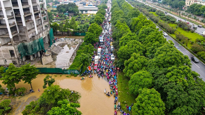 Ảnh: Đại lộ Thăng Long ngập sâu trong nước, hàng nghìn người dân vất vả dắt xe đi làm - Ảnh 1.